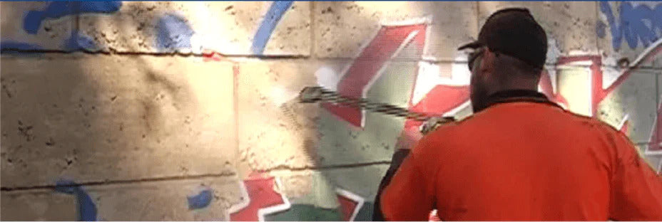 Man removing graffiti from a anti-graffiti coated wall