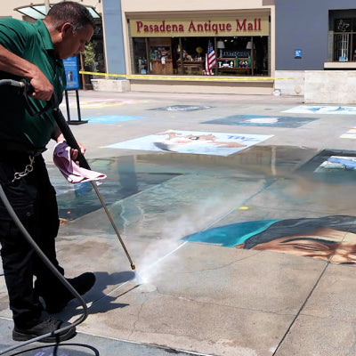 Man pressure washes chalk from concrete