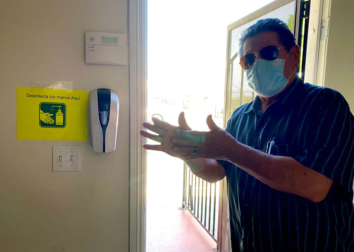 
Man sanitizing his hands using liquid dispenser
